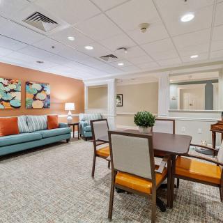 A cozy living area with a dining table and chairs, complemented by a sofa and decorative artwork on the walls.