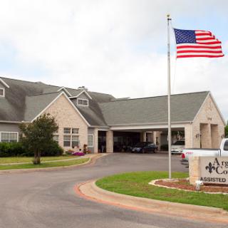A welcoming entrance of a care facility with the American flag proudly displayed.
