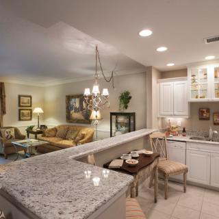 A modern open-concept kitchen and living room with granite countertops and elegant lighting.