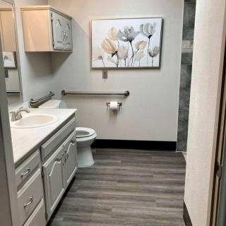 A modern bathroom with a white sink, toilet, and floral artwork on the wall.