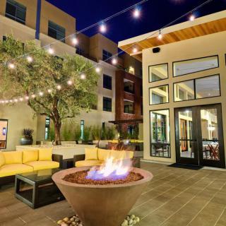 A cozy outdoor patio with a fire pit and string lights at night.