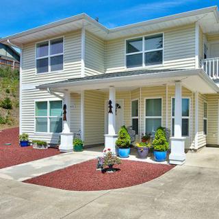 A modern two-story house with a porch, surrounded by a landscaped front yard and driveway.