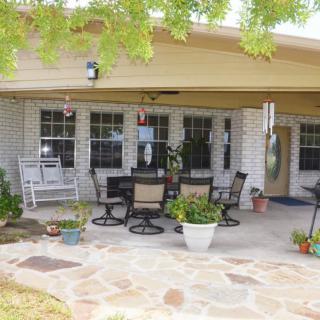 A cozy patio with outdoor furniture and potted plants under a covered porch.