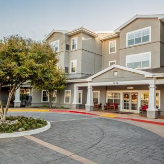 A multi-story residential building with a landscaped entrance and driveway.