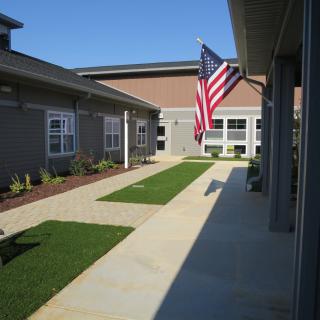 A sunny courtyard with an American flag displayed prominently between two buildings.