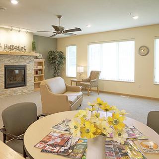 A cozy living room interior featuring comfortable seating, a fireplace, and a table with magazines.
