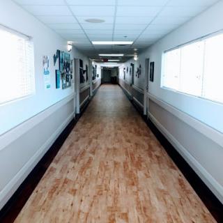 A well-lit hallway featuring artwork on the walls and a wooden floor.