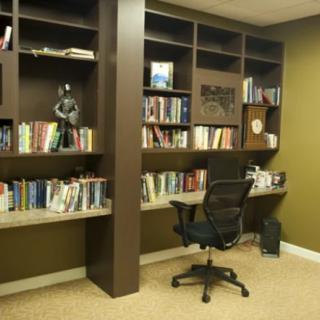 A neatly organized home office with bookshelves, a comfortable chair, and a desk.