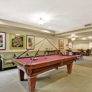 A well-furnished recreation room featuring a pool table, comfortable seating, and framed artwork on the walls.