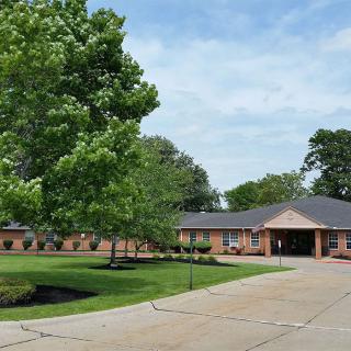 A view of a brick school building surrounded by trees and a driveway.