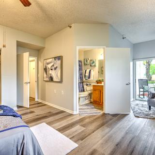 A cozy bedroom with wood flooring, a doorway leading to a bathroom, and sliding doors opening to an outdoor area.