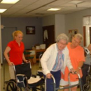 Caregivers assist elderly individuals with walkers in a supportive environment.