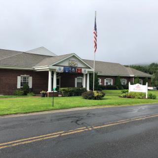 A view of a brick building with landscaping, featuring an American flag in front.