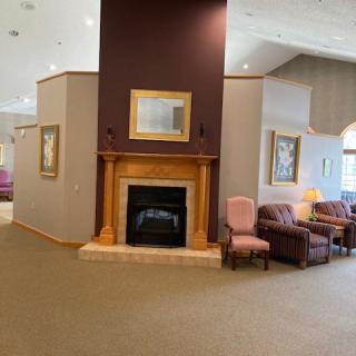 A cozy interior living space featuring a central fireplace with surrounding chairs and couches.