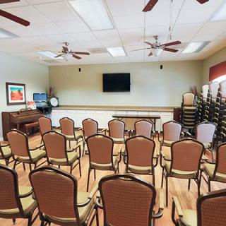 An empty conference room with arranged chairs and a television on the wall.