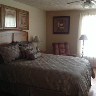 A cozy bedroom with a large bed, decorative pillows, and a standing lamp.