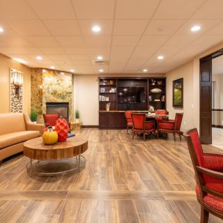 A warmly lit modern living room with a seating area, featuring wooden floors and cozy furniture.