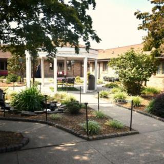 A serene courtyard garden with a central pavilion surrounded by lush greenery.