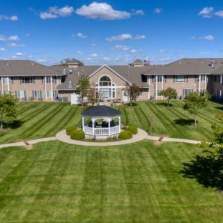 A large, symmetrical building with a well-maintained lawn and a central gazebo under a blue sky with scattered clouds.