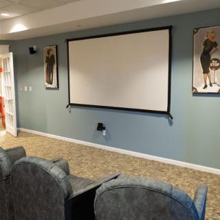A cozy home theater setup with comfortable seating and a large projector screen.
