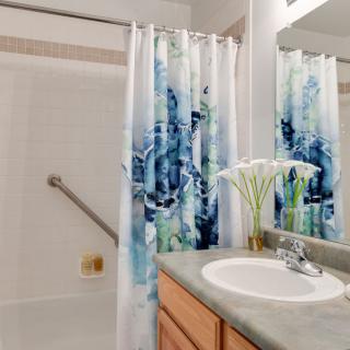 A tidy bathroom featuring a sink with a floral arrangement and a patterned shower curtain.