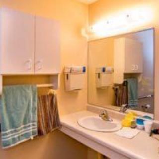A clean bathroom with a sink, a large mirror, and neatly hung towels.