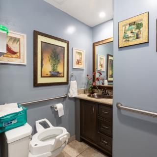A modern bathroom with decorative artwork, featuring a sink, toilet, and mirror.
