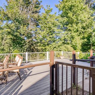 A sunny outdoor deck with patio furniture surrounded by lush greenery.