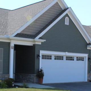 A suburban house with a double garage and green siding.