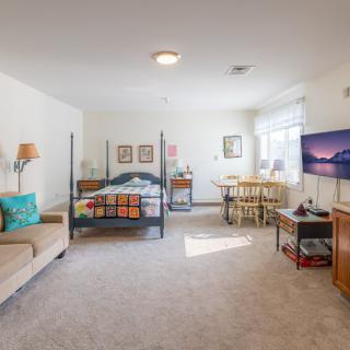 A spacious bedroom with a bed, sofa, television, and large windows.