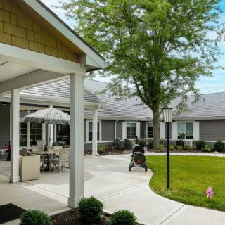 A peaceful outdoor area with a patio, well-maintained garden, and walkway surrounded by buildings.