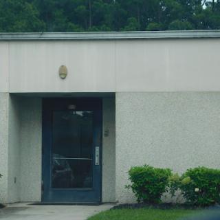 A simple building entrance surrounded by greenery.