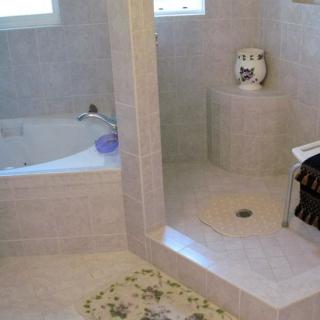 A modern bathroom with a tiled bathtub and shower area.