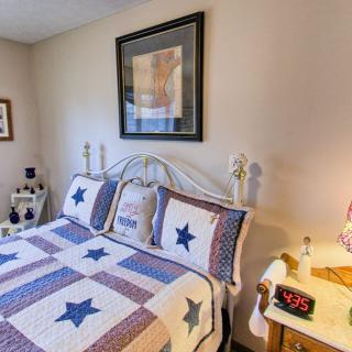 A cozy bedroom featuring a bed with a star-patterned quilt, surrounded by warm decor and furniture.