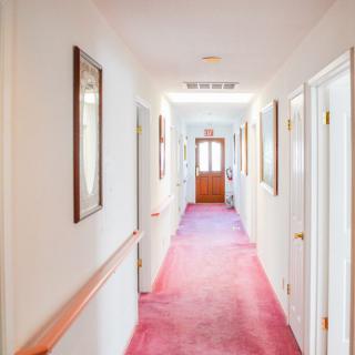A brightly lit hallway with a red carpet and multiple doors on each side.