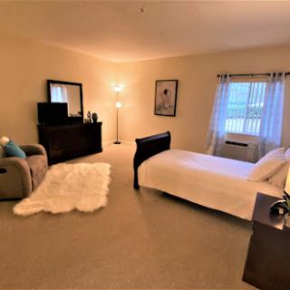 A cozy and modern bedroom featuring a bed, armchair, and natural light filtering through the window.