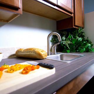 A modern kitchen with a countertop featuring a sink, bread, and chopped vegetables on a cutting board.
