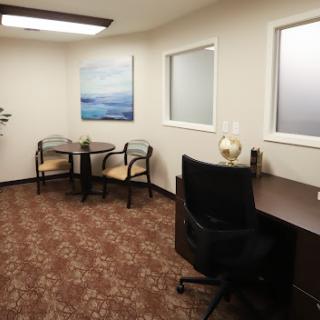 A modern office interior featuring a desk, seating area, and artwork.