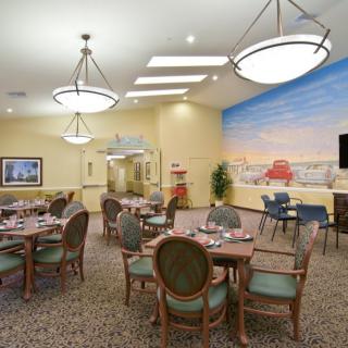 A well-lit dining area with neatly arranged tables and chairs, featuring a large mural on the wall.