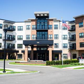 A modern apartment building with multiple floors and a flag displayed outside, captured on a clear day.
