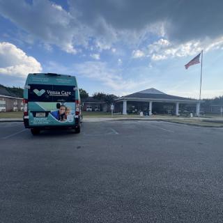 A colorful truck parked outside a building with an American flag waving in the background.