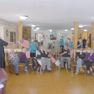 Seniors enjoying a lively community event, proudly waving American flags.