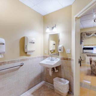 A clean and organized restroom with a sink, toilet, and hand dryers.