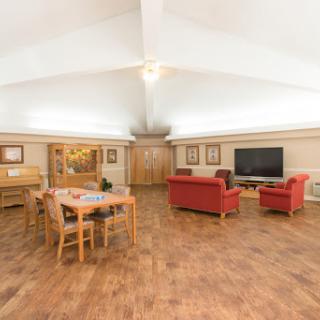 A spacious and modern living room featuring red sofas, a dining area, and a large TV.