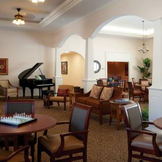 A cozy living room with a piano and seating area, featuring a chessboard on the table.