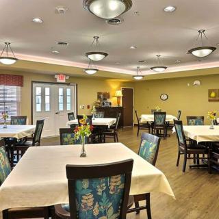 A well-lit dining room with neatly arranged tables and chairs.