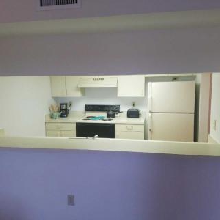 A view of a kitchen with various appliances including a refrigerator, stove, coffee maker, and toaster.