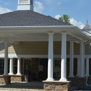 A modern building featuring elegant columns and a stylish roof under a clear blue sky.