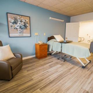 A well-furnished hospital room featuring a medical bed, comfortable chair, and elegant decor.