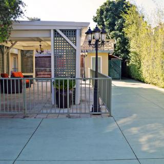 A spacious backyard with a paved area, outdoor seating, and greenery.